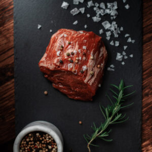 beef filet mignon on a black stone cutting board with salt