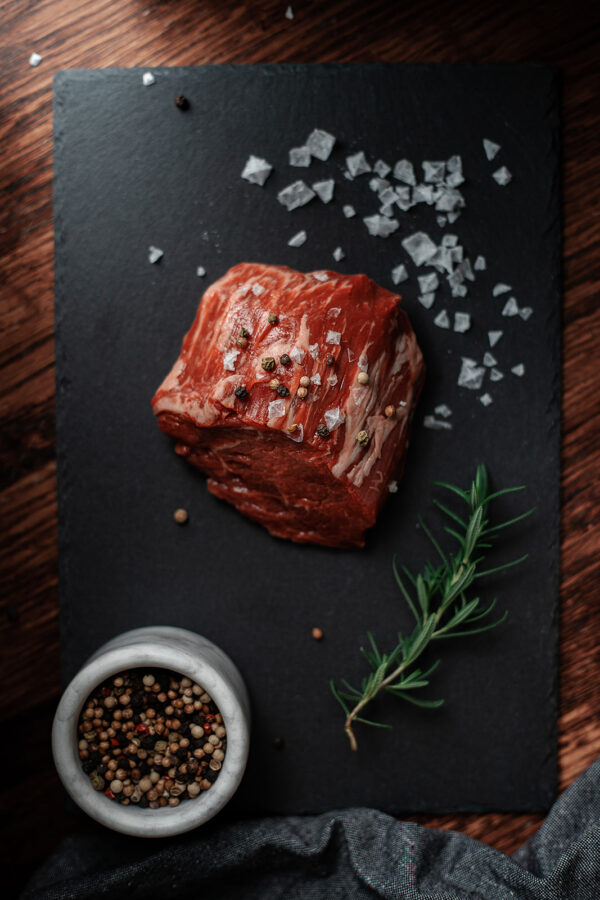 beef filet mignon on a black stone cutting board with salt